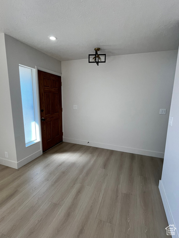 Unfurnished dining area with recessed lighting, a textured ceiling, light wood finished floors, and baseboards