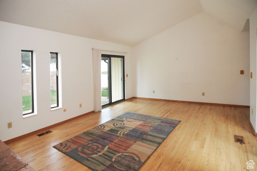 Spare room with baseboards, lofted ceiling, visible vents, and wood finished floors