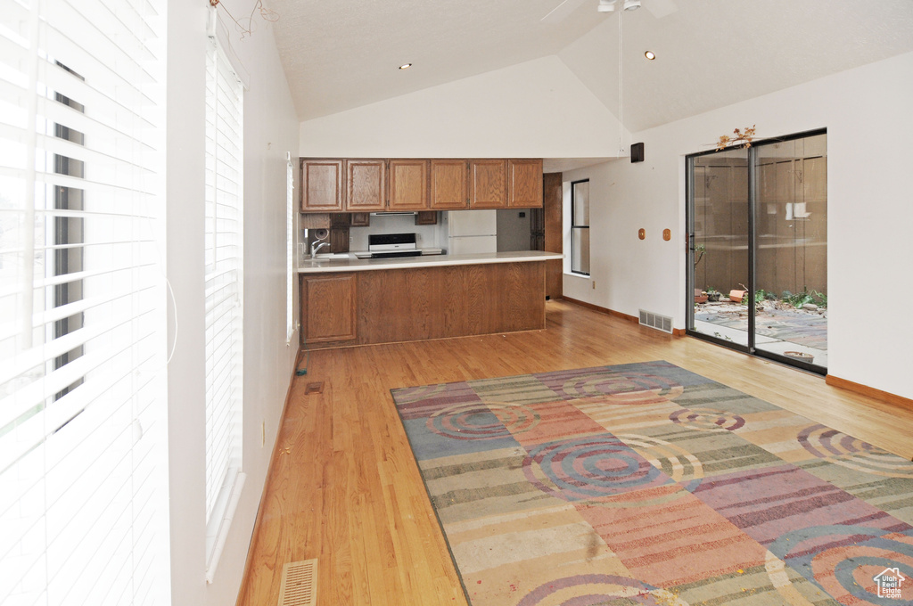 Kitchen with light countertops, visible vents, a peninsula, light wood finished floors, and brown cabinets