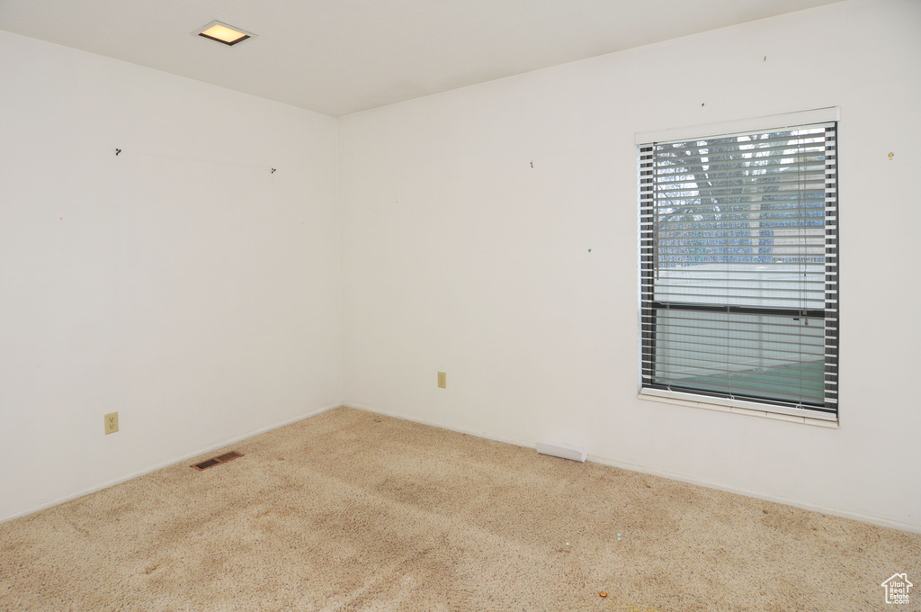 Carpeted empty room featuring visible vents
