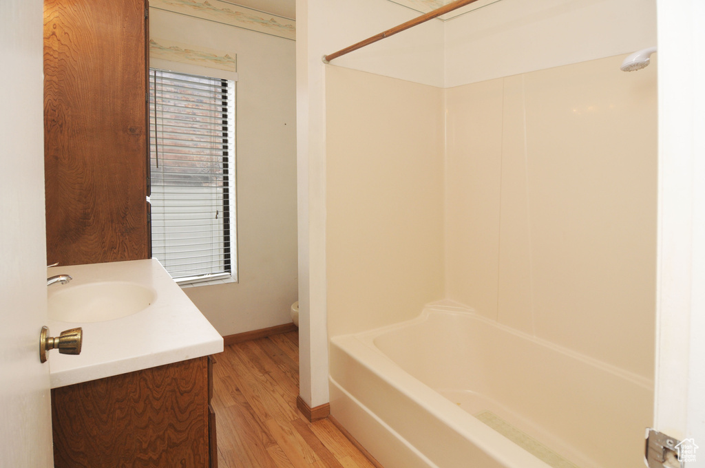 Full bath featuring baseboards, toilet, wood finished floors, vanity, and shower / bathing tub combination
