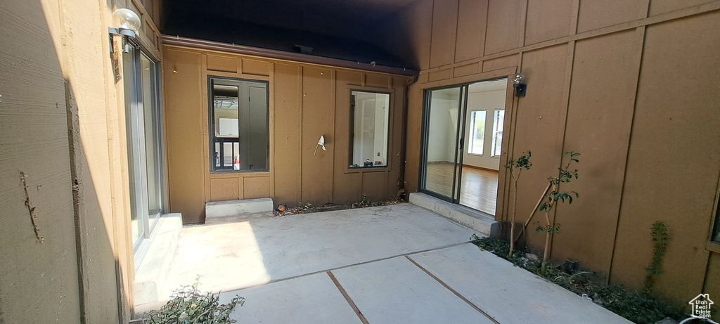 View of exterior entry with board and batten siding and a patio area
