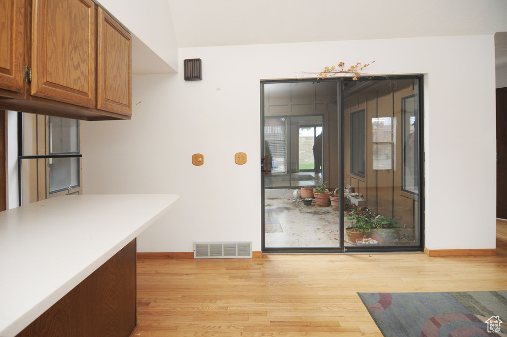 Kitchen featuring light countertops, visible vents, light wood finished floors, baseboards, and brown cabinets