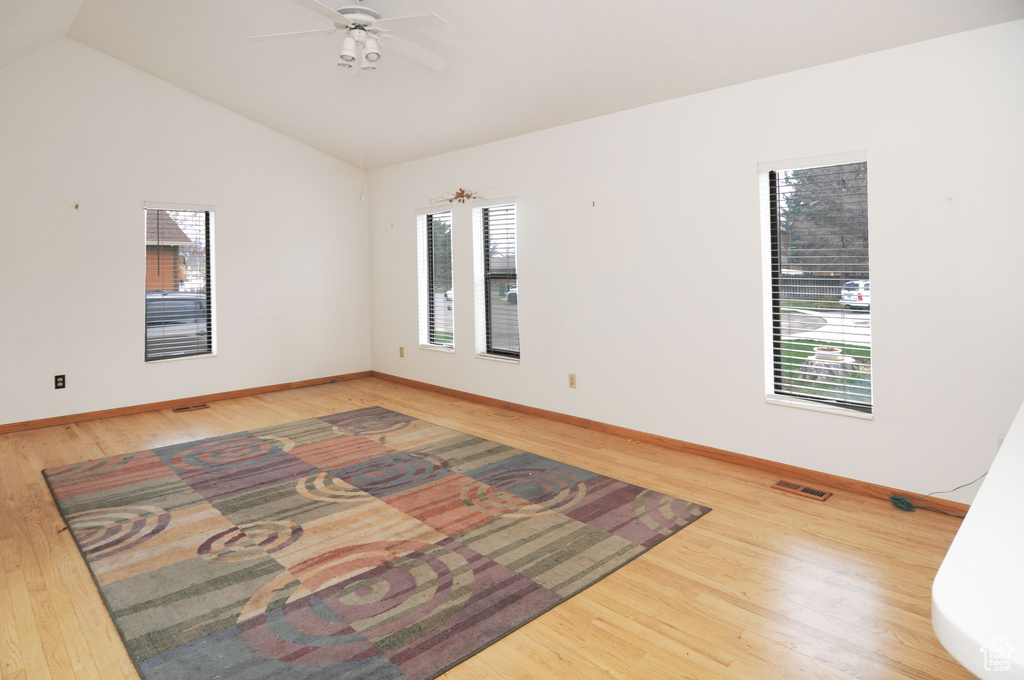 Unfurnished room featuring visible vents, baseboards, ceiling fan, wood finished floors, and lofted ceiling