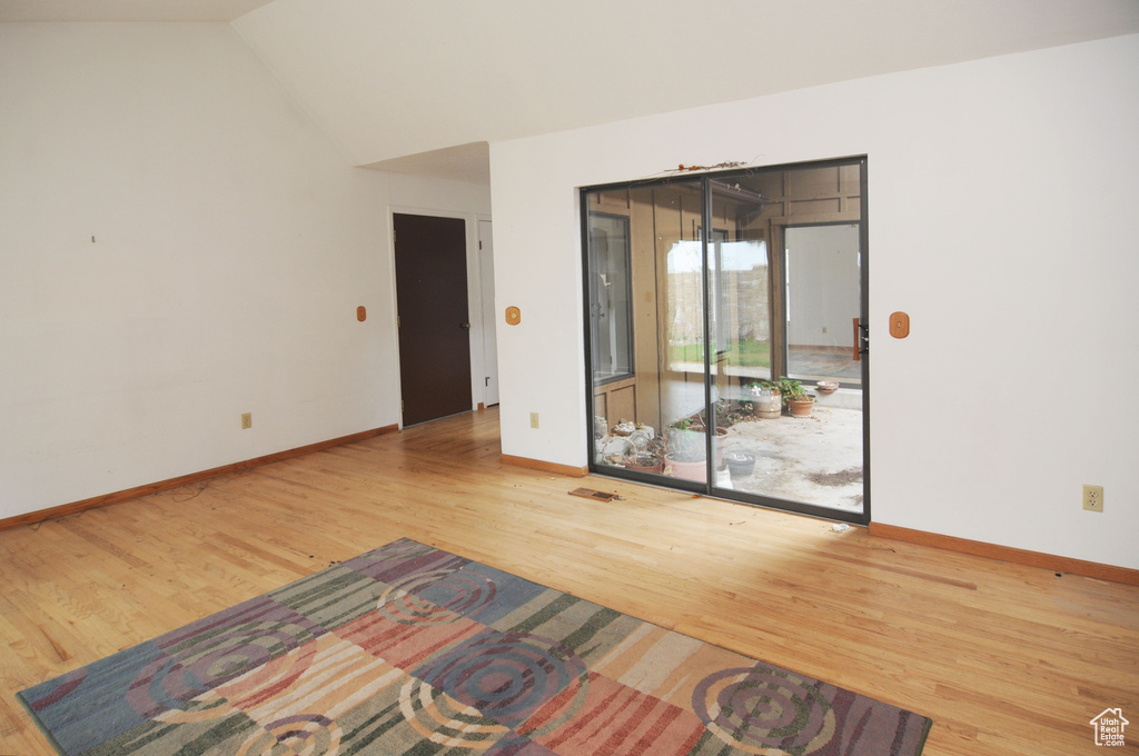 Spare room with visible vents, baseboards, vaulted ceiling, and wood finished floors