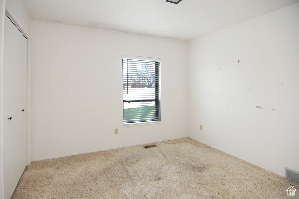 Empty room featuring carpet and visible vents