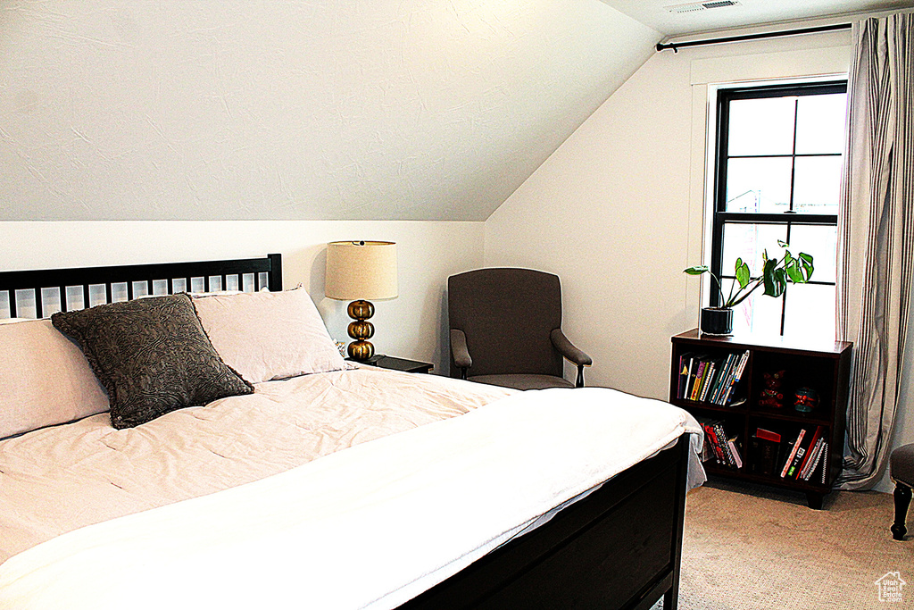 Bedroom featuring light carpet and vaulted ceiling