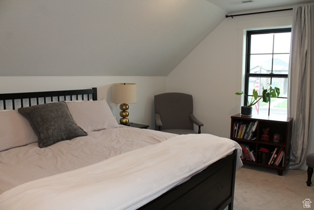 Bedroom with lofted ceiling and light carpet