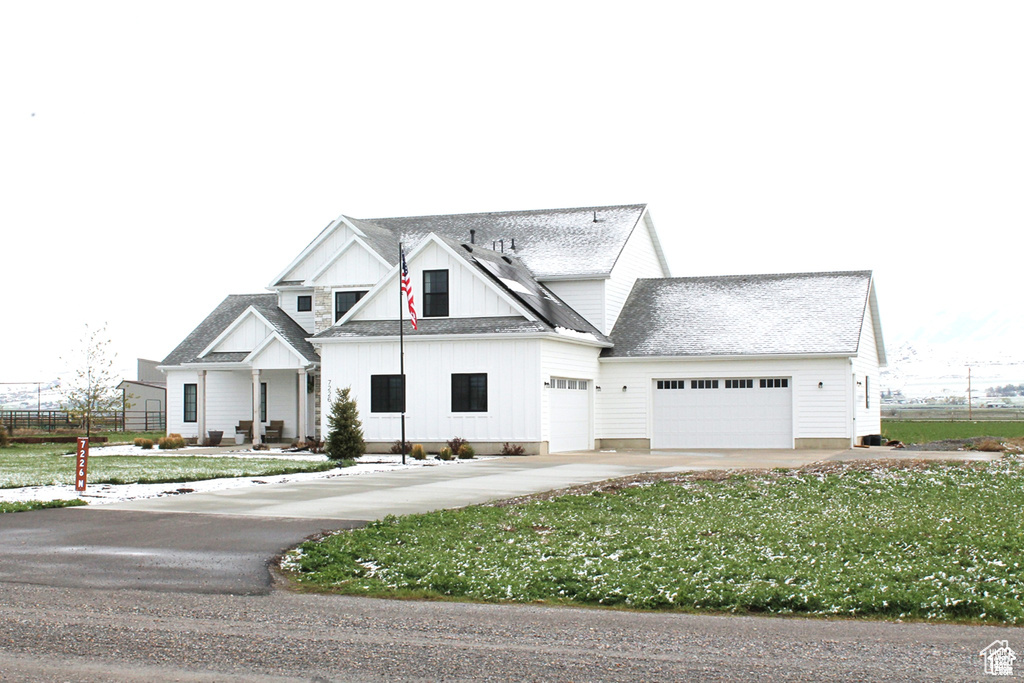 Modern farmhouse with an attached garage, a front yard, fence, and driveway