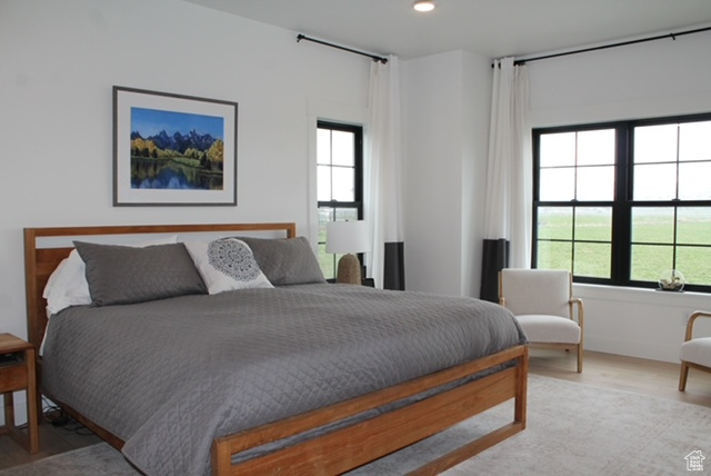 Bedroom with wood finished floors, multiple windows, and recessed lighting