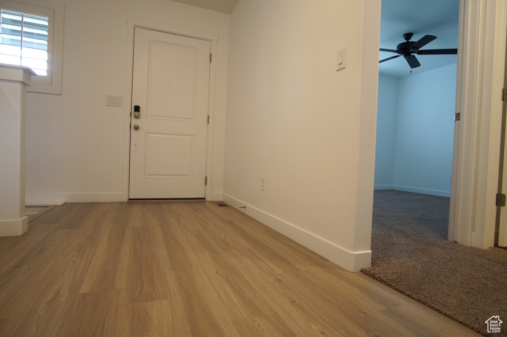 Entrance foyer with light wood finished floors, a ceiling fan, and baseboards