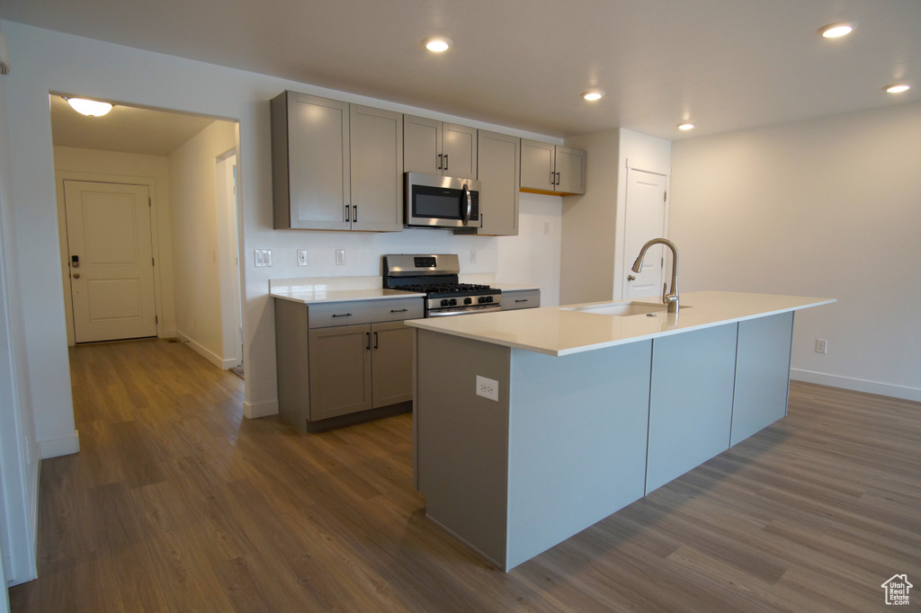 Kitchen with a sink, dark wood finished floors, appliances with stainless steel finishes, and gray cabinets