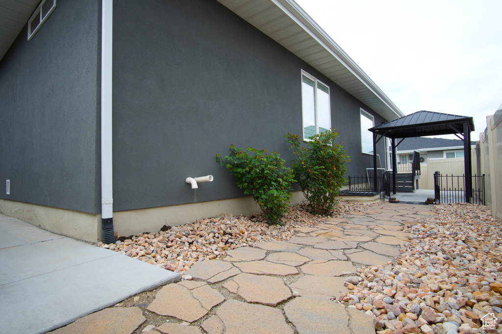 View of property exterior featuring stucco siding, a gazebo, fence, and a patio area