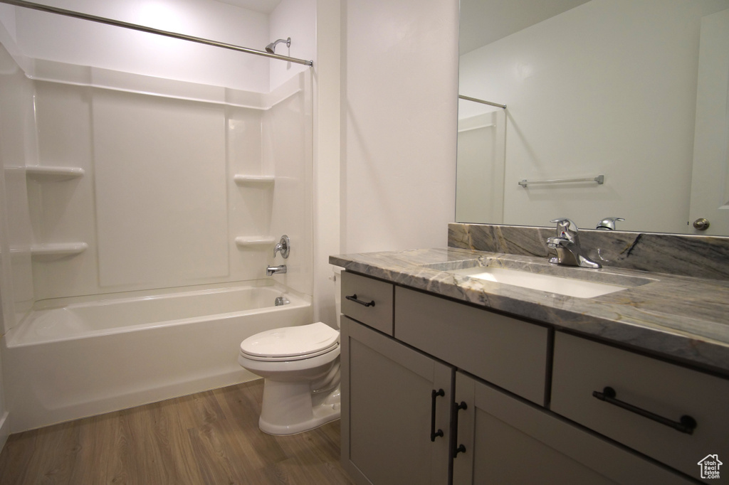 Bathroom with wood finished floors, vanity, washtub / shower combination, and toilet