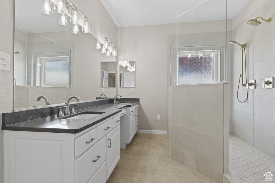 Full bath with walk in shower, double vanity, and tile patterned floors