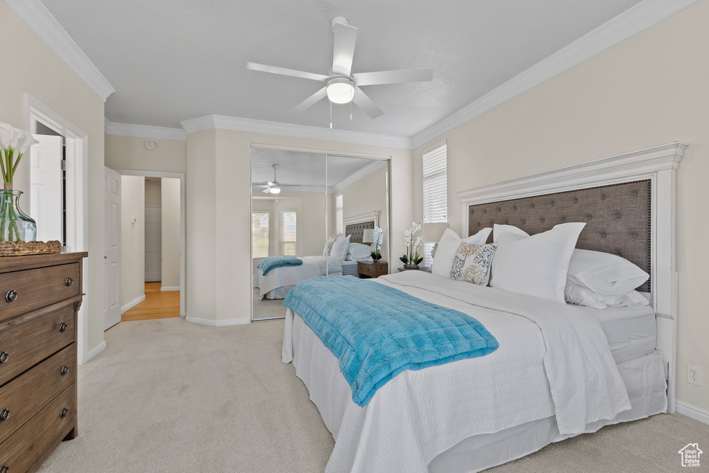 Bedroom with crown molding, light colored carpet, a closet, baseboards, and ceiling fan