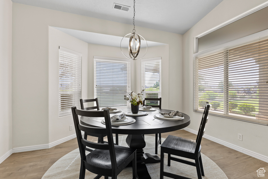 Dining room with light wood-style floors, baseboards, and a chandelier