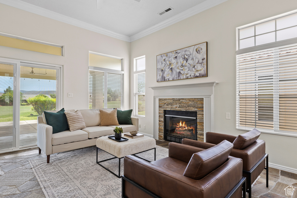 Living area with ornamental molding, a stone fireplace, and baseboards