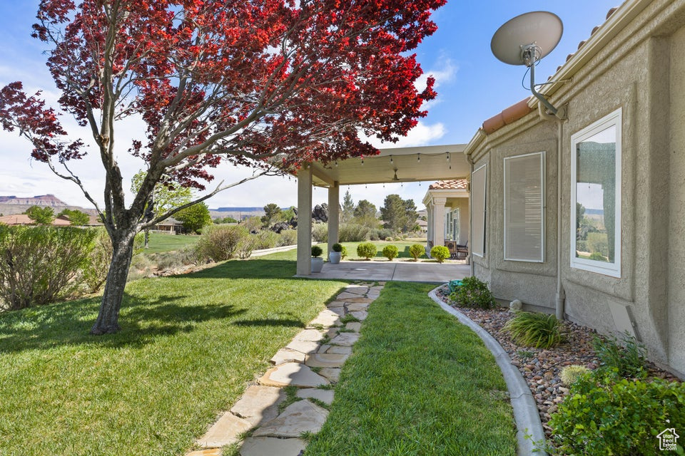 View of grassy yard featuring a patio area