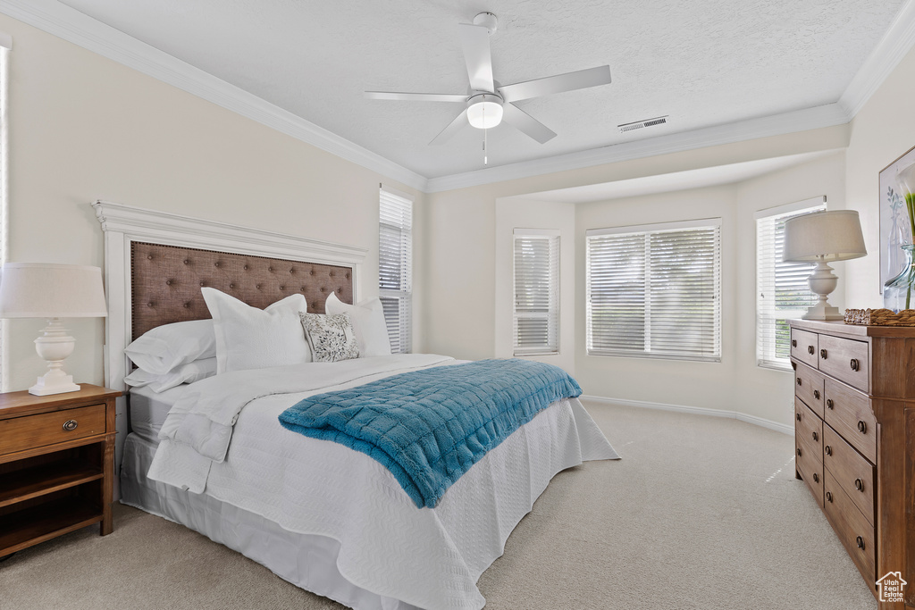 Bedroom with light colored carpet, ornamental molding, multiple windows, ceiling fan, and baseboards