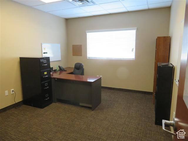 Office area featuring dark carpet, visible vents, and a drop ceiling