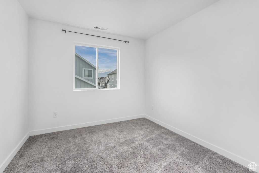 Carpeted spare room with visible vents and baseboards