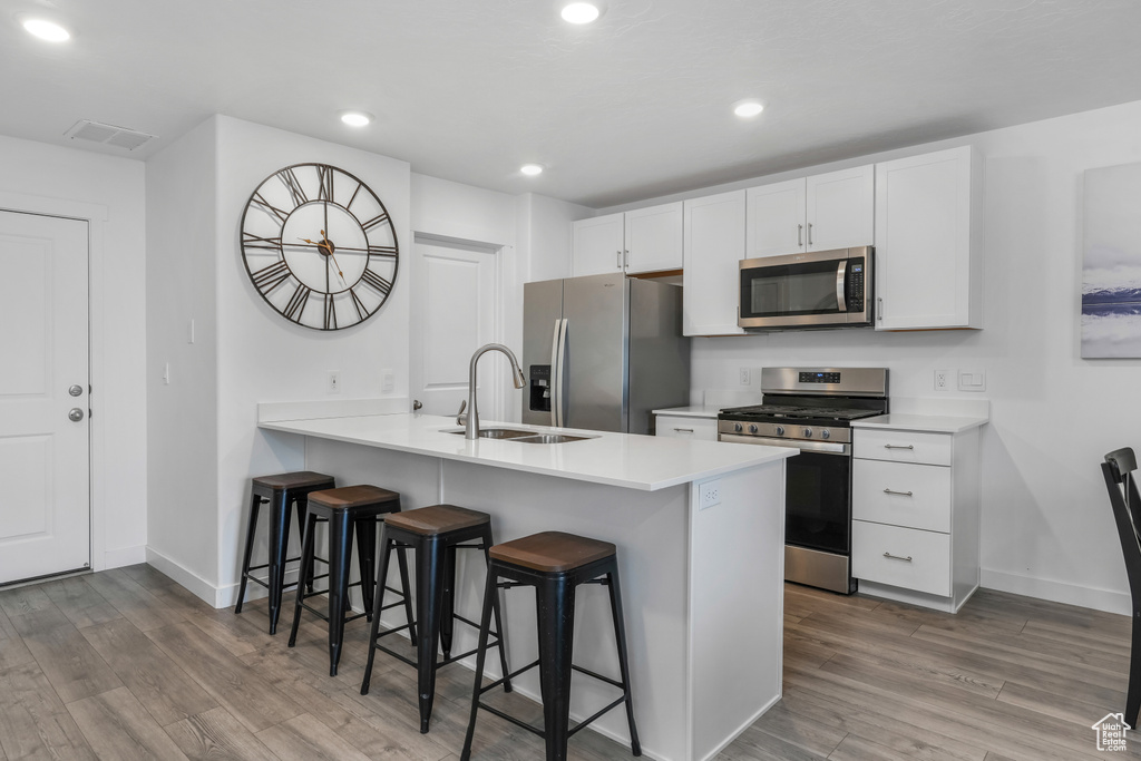 Kitchen featuring a sink, stainless steel appliances, a kitchen bar, baseboards, and visible vents