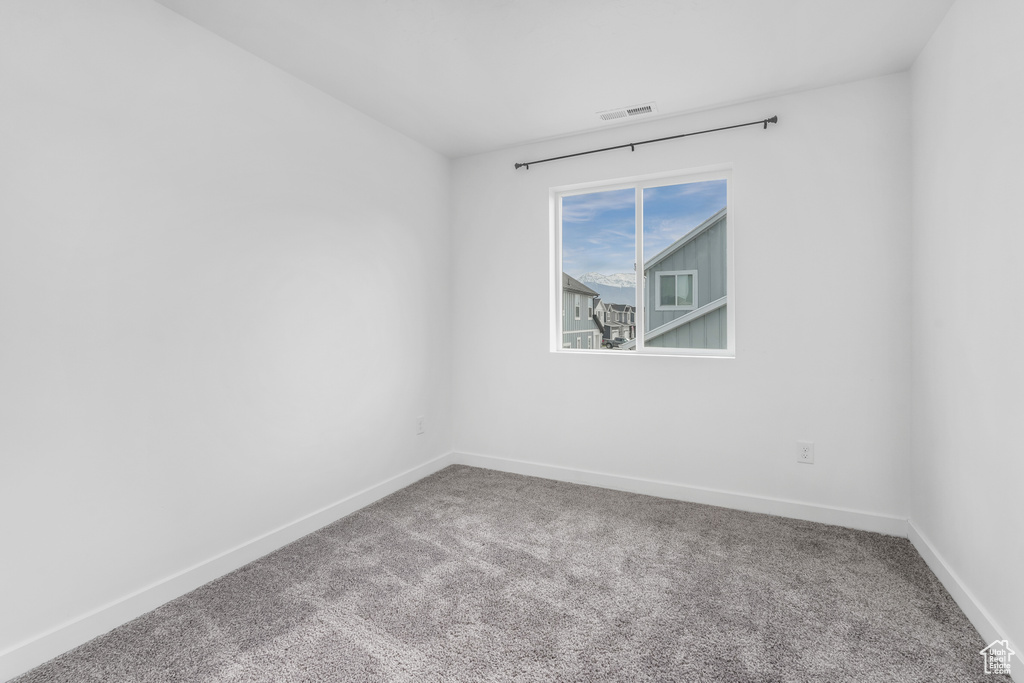 Spare room featuring carpet floors, visible vents, and baseboards