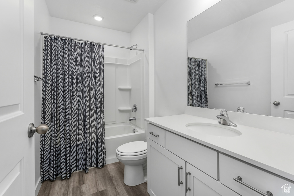 Full bathroom featuring shower / bath combination with curtain, toilet, vanity, and wood finished floors