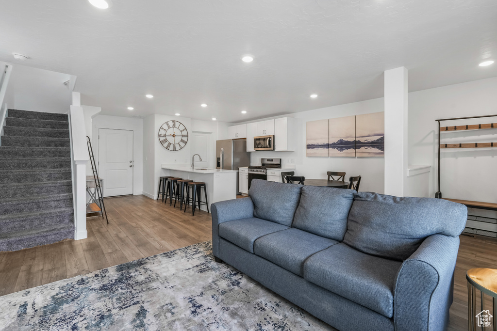 Living room with stairway, recessed lighting, and light wood-type flooring