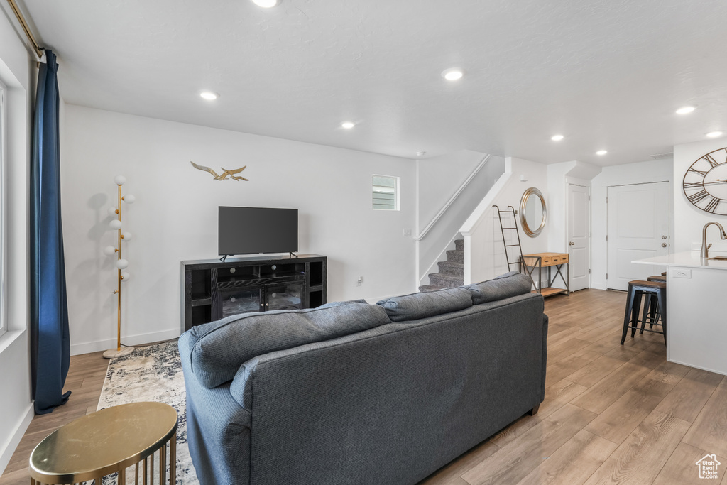 Living area with stairway, baseboards, wood finished floors, and recessed lighting