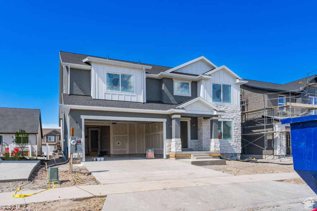View of front of house with driveway, a garage, board and batten siding, and stone siding