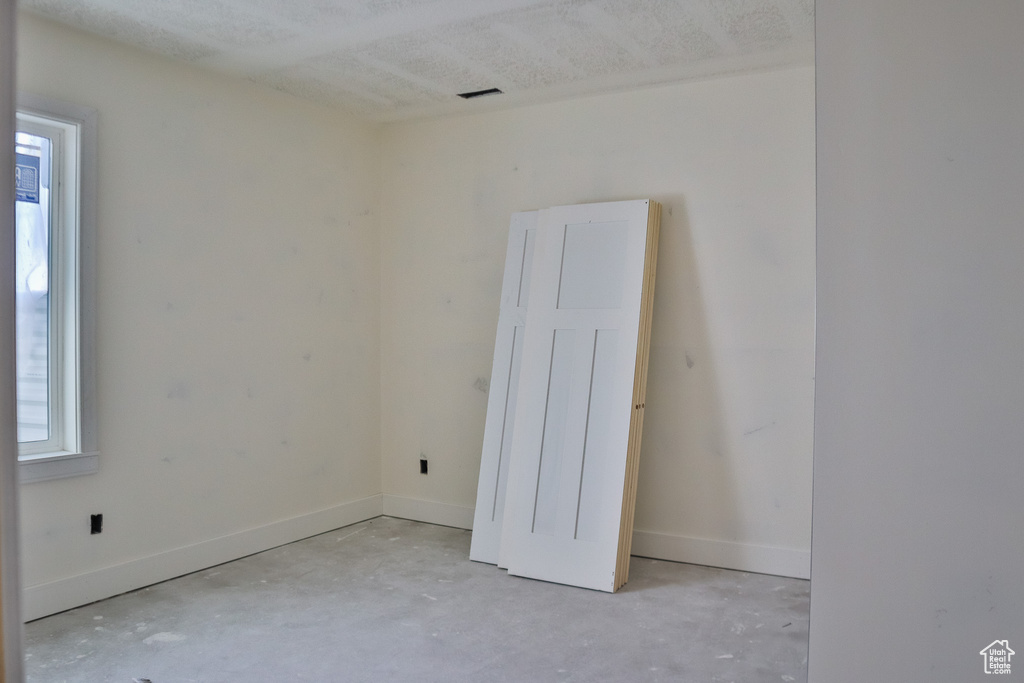 Unfurnished room with unfinished concrete flooring