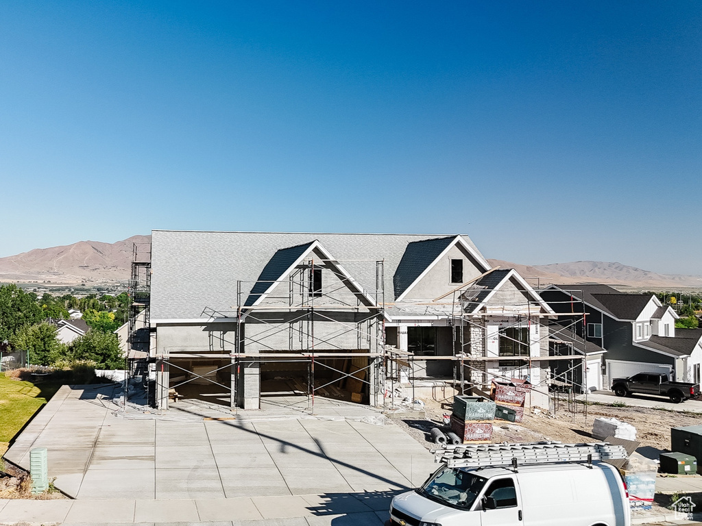 Back of property featuring a mountain view, driveway, and a residential view