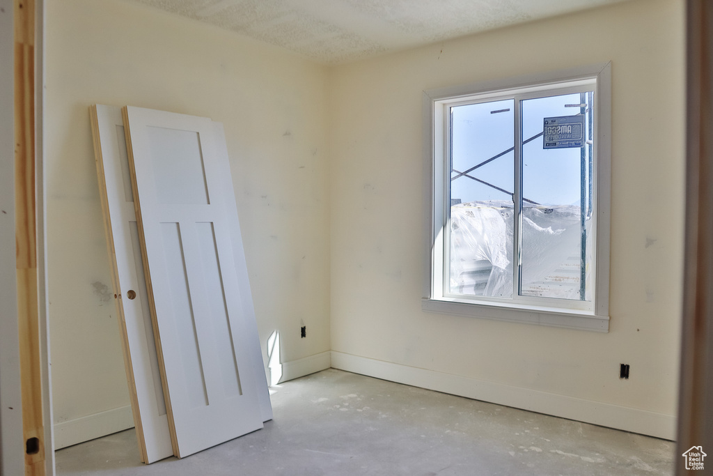 Empty room featuring healthy amount of natural light and concrete floors