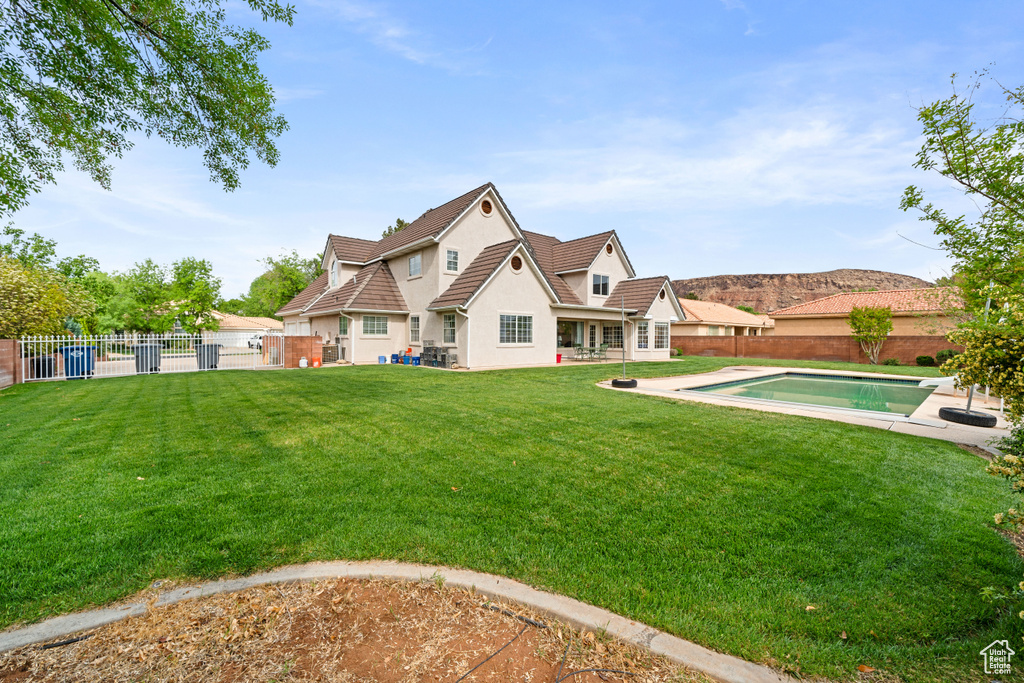 Rear view of property featuring a fenced backyard, a lawn, a fenced in pool, and stucco siding
