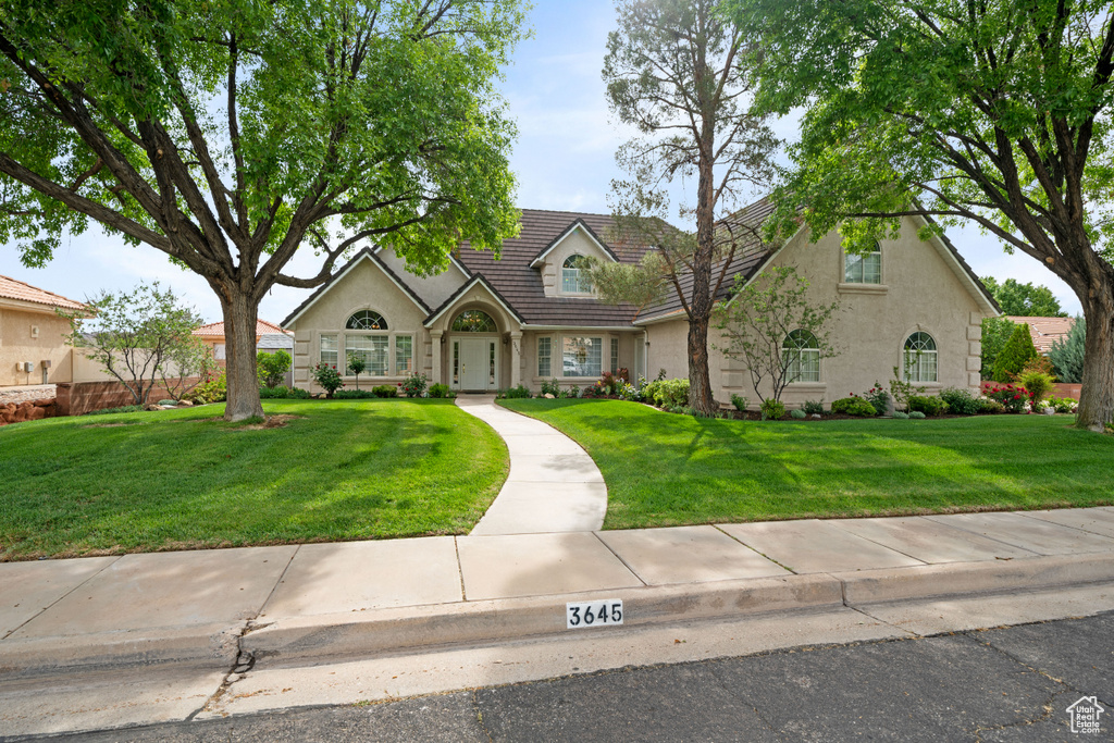 View of front of home featuring stone siding, a tiled roof, a front lawn, and stucco siding