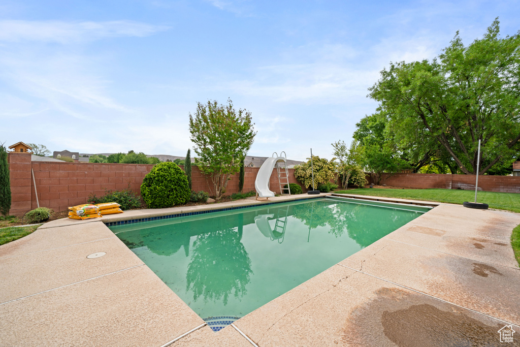 View of swimming pool featuring a fenced backyard, a water slide, a fenced in pool, and a patio