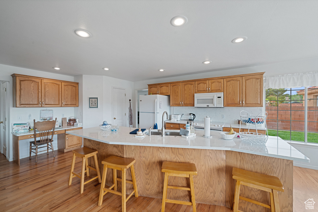 Kitchen with recessed lighting, light wood finished floors, white appliances, and light countertops