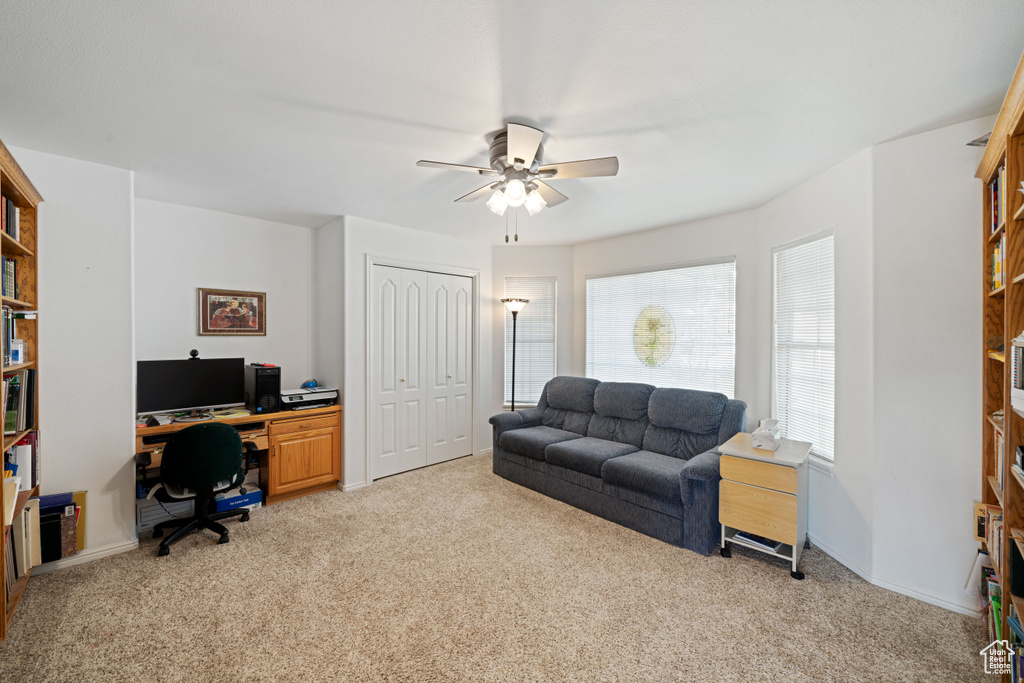 Office area featuring a ceiling fan, baseboards, and light colored carpet