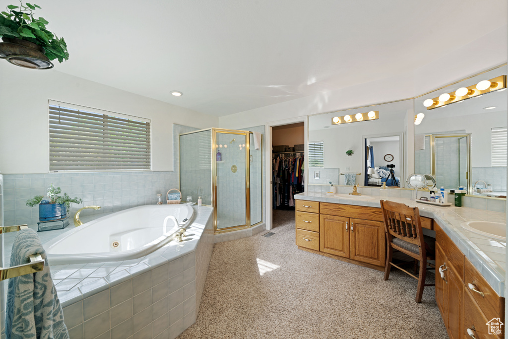Full bathroom with a jetted tub, a spacious closet, vanity, and a stall shower