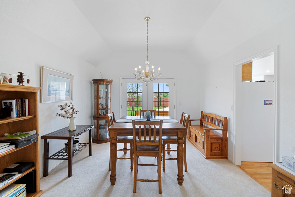 Dining room with a chandelier, vaulted ceiling, and light carpet