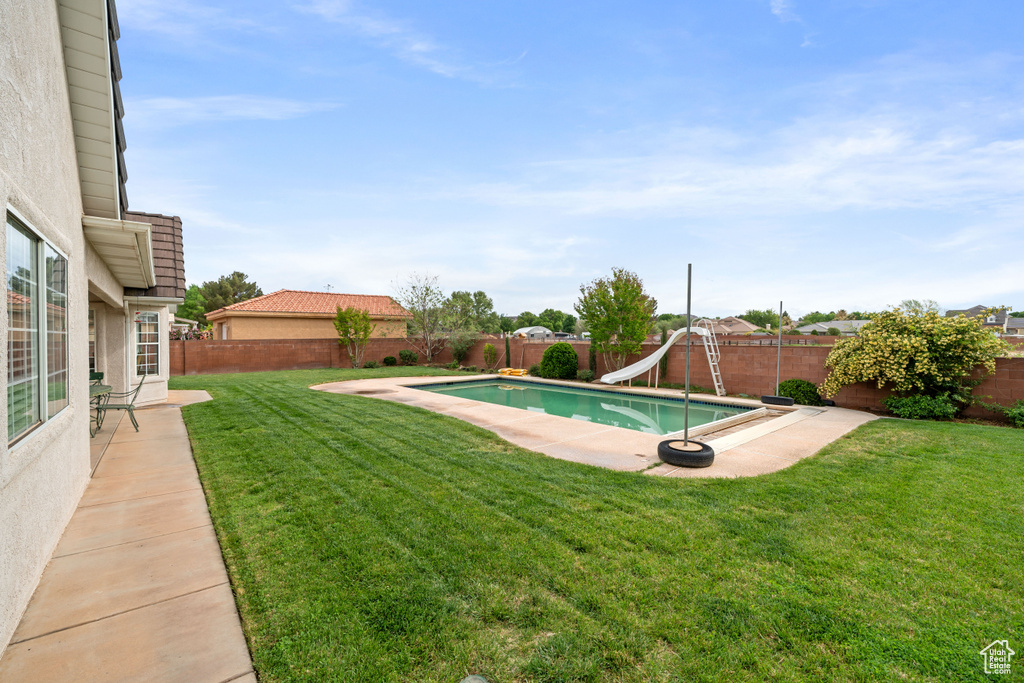 View of swimming pool featuring a water slide, a fenced in pool, a fenced backyard, and a lawn