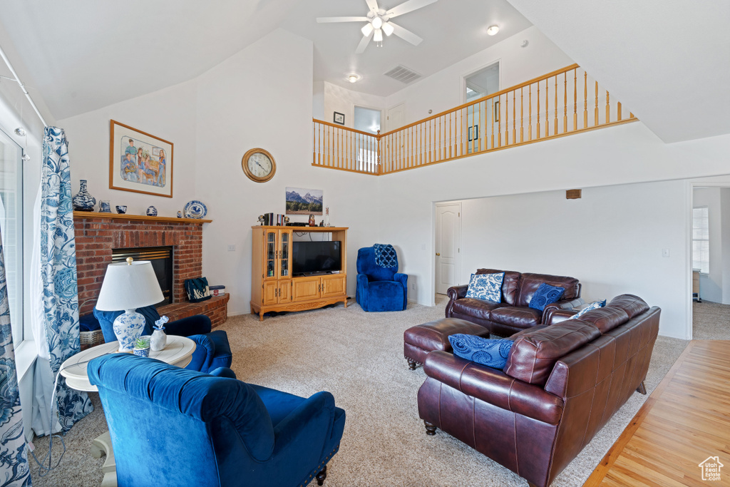 Carpeted living area with high vaulted ceiling, a ceiling fan, visible vents, and a fireplace
