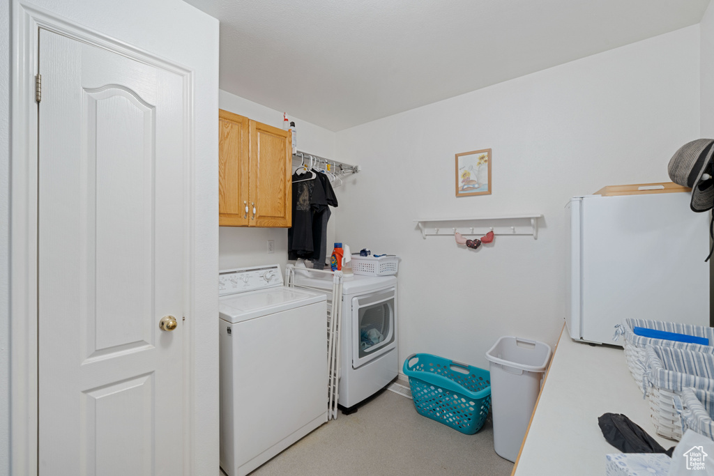 Laundry room with cabinet space, light carpet, and washer and clothes dryer