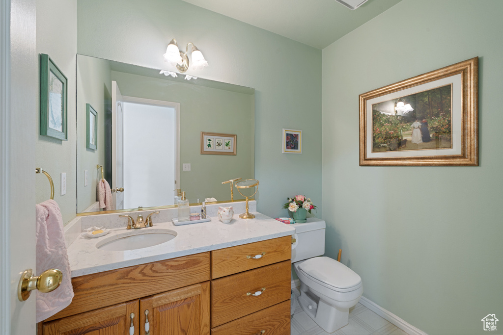 Bathroom featuring baseboards, vanity, tile patterned flooring, and toilet