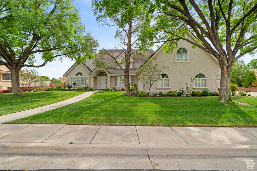 Tudor house featuring stucco siding, a front lawn, and a tile roof