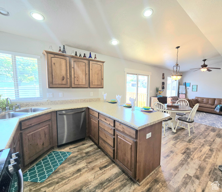 Kitchen with stainless steel dishwasher, a sink, wood finished floors, black stove, and a peninsula