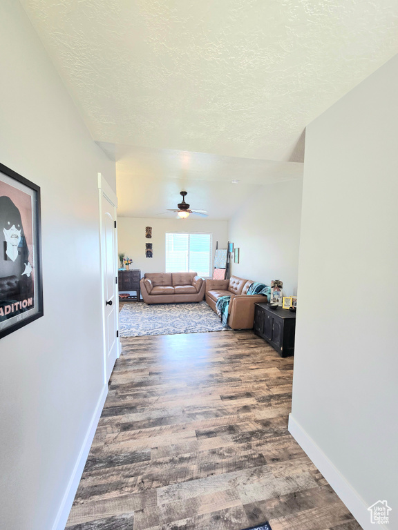 Hall with a textured ceiling, baseboards, and wood finished floors