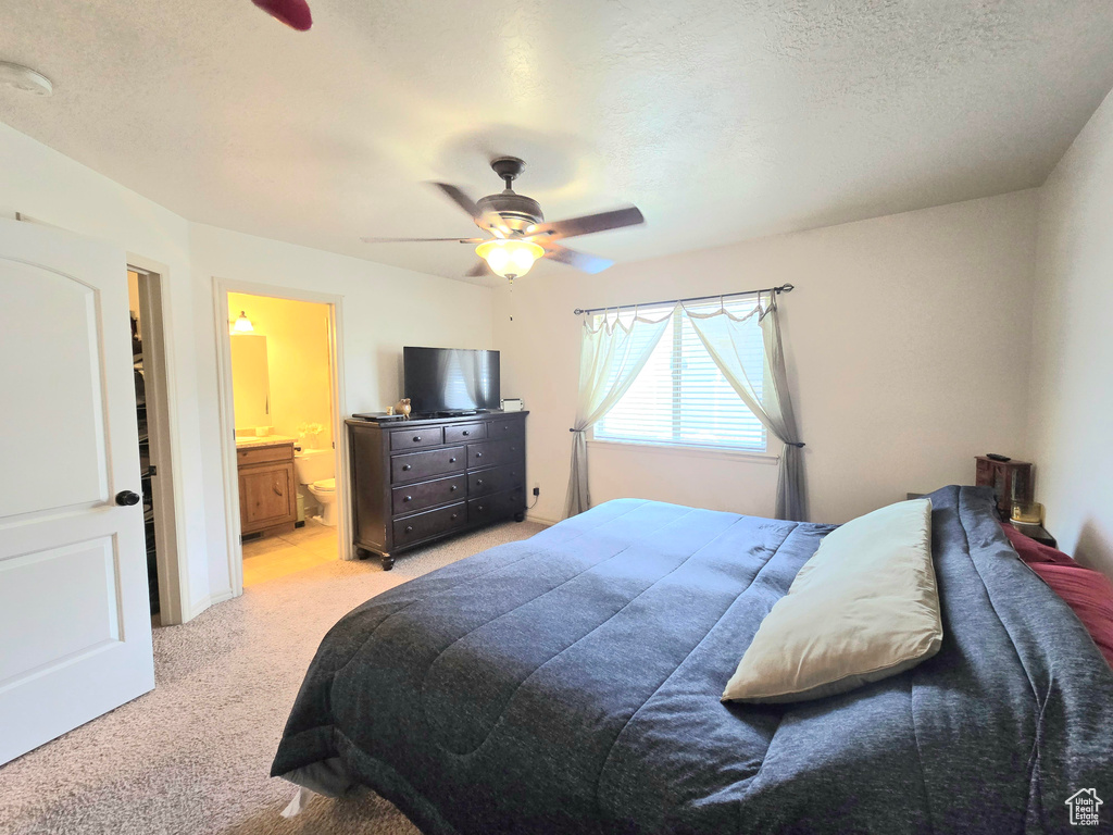 Bedroom featuring light carpet, connected bathroom, and ceiling fan